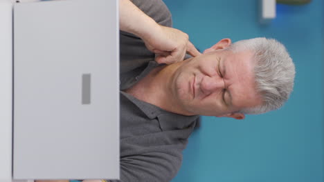 Vertical-video-of-Home-office-worker-man-scratches-his-ears-looking-at-camera.